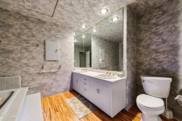 a kitchen with stainless steel appliances kitchen island granite countertop a refrigerator a stove top oven a dining table and chairs with wooden floor