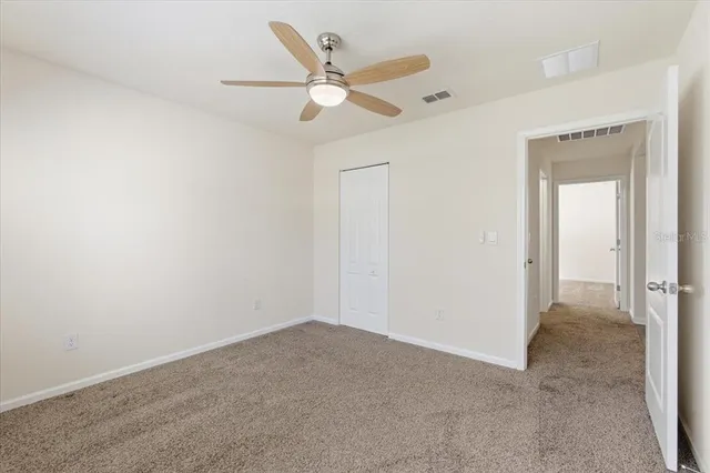 an empty room with closet and a chandelier fan
