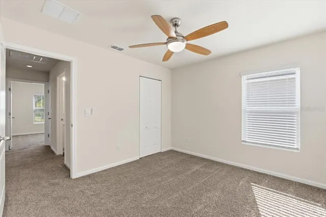 an empty room with a ceiling fan and window