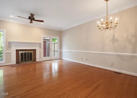a view of an empty room with wooden floor fireplace and a window