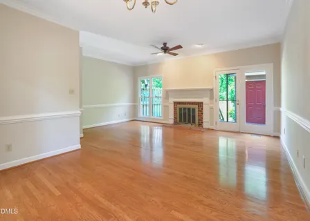 an empty room with wooden floor fireplace and windows