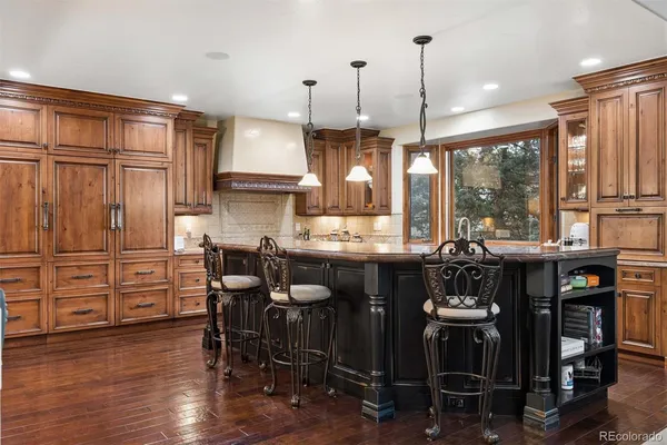 a kitchen with stainless steel appliances granite countertop a stove a refrigerator a sink a dining table and chairs with wooden floor