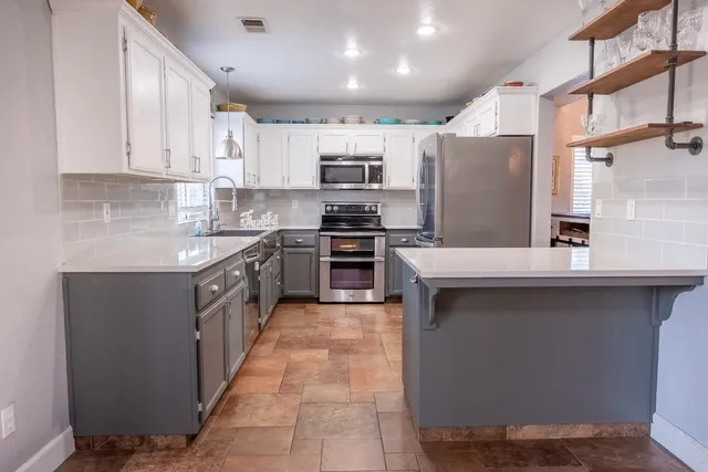 a kitchen with stainless steel appliances granite countertop a sink counter space cabinets and a large window