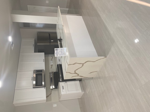 183 Mimosa Road Dale, TX 78616 - Photo 3 of 11 Kitchen featuring a waterfall island with a unique veined countertop, stainless steel appliances, white cabinetry, and light-toned tile flooring