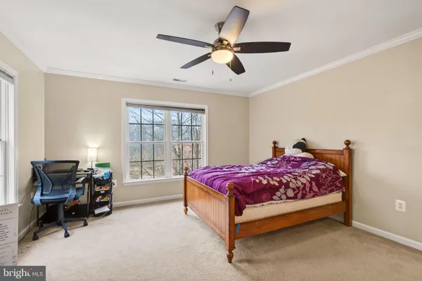 a bedroom with a large bed and a chandelier fan