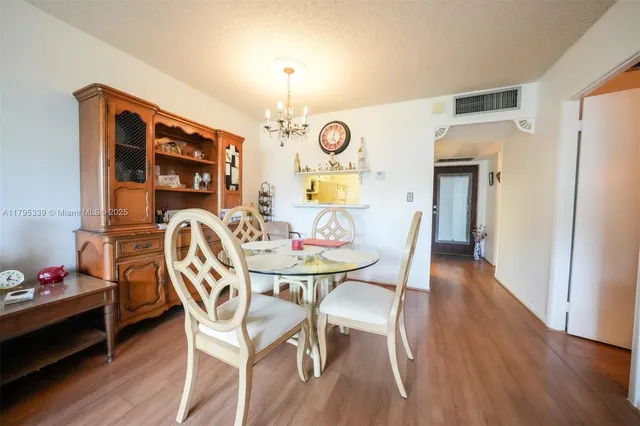 a dining room with wooden floor chandeliers and furniture