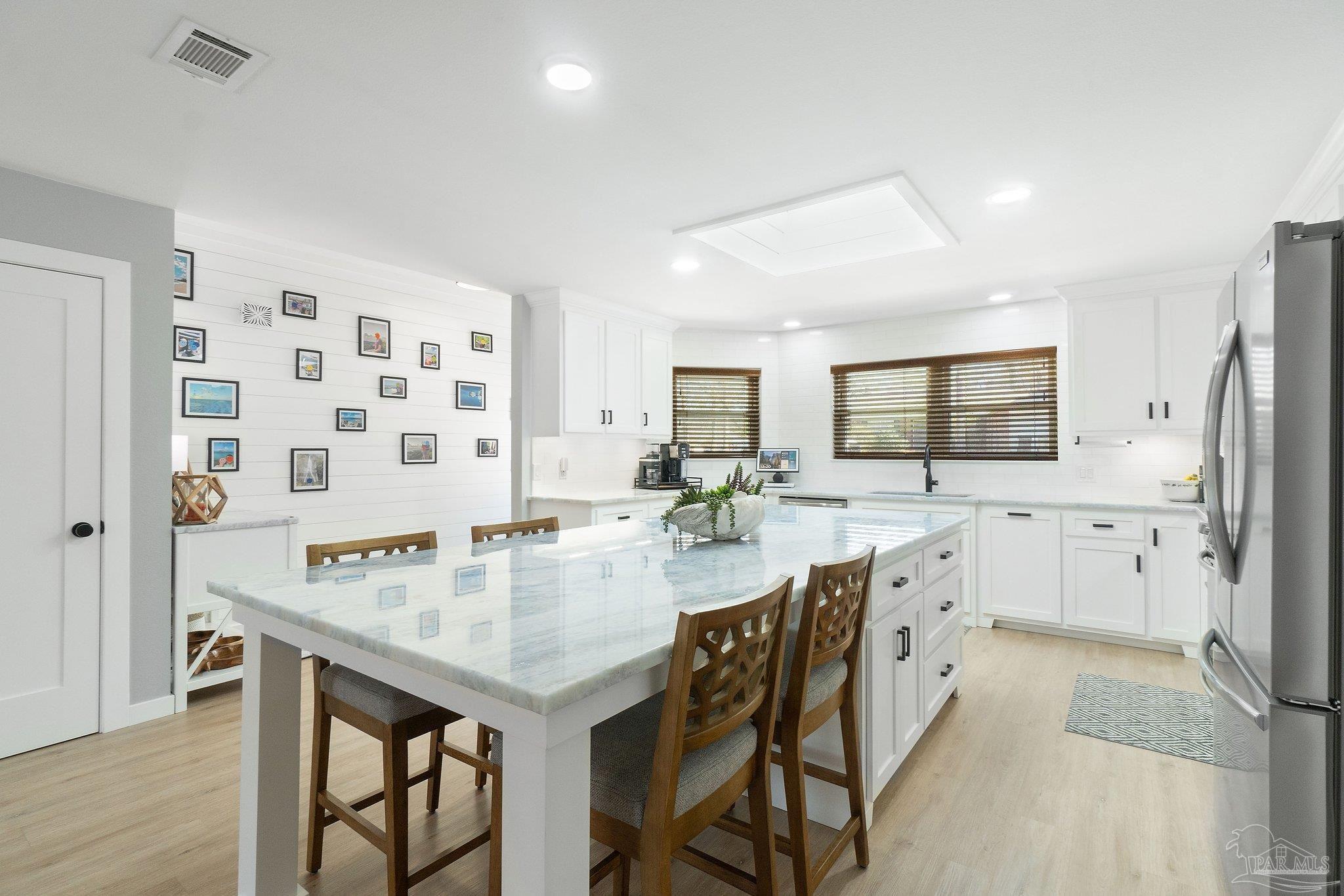 2016 Winners Circle Cantonment, FL 32533 - Photo 9 of 32 a kitchen with stainless steel appliances kitchen island granite countertop a table chairs in it and white cabinets