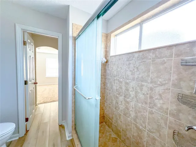 a bathroom with a glass door shower and a toilet