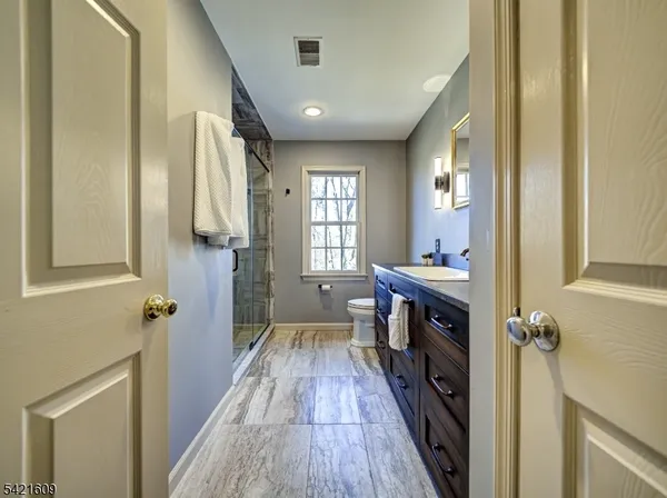 a bathroom with a sink a toilet a mirror and a window