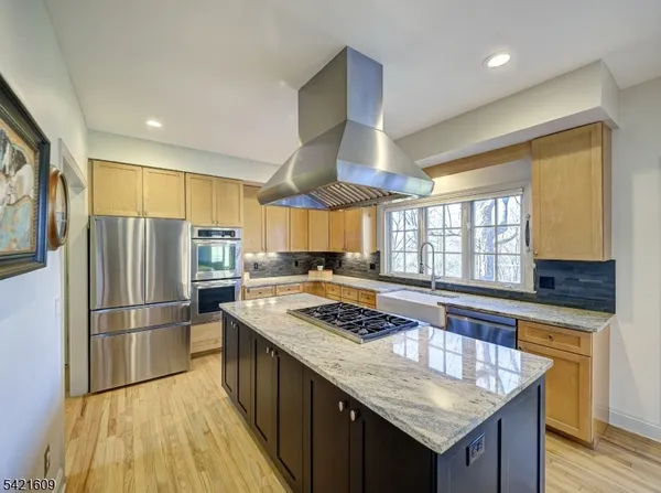 a kitchen with granite countertop stainless steel appliances a refrigerator stove and wooden floor