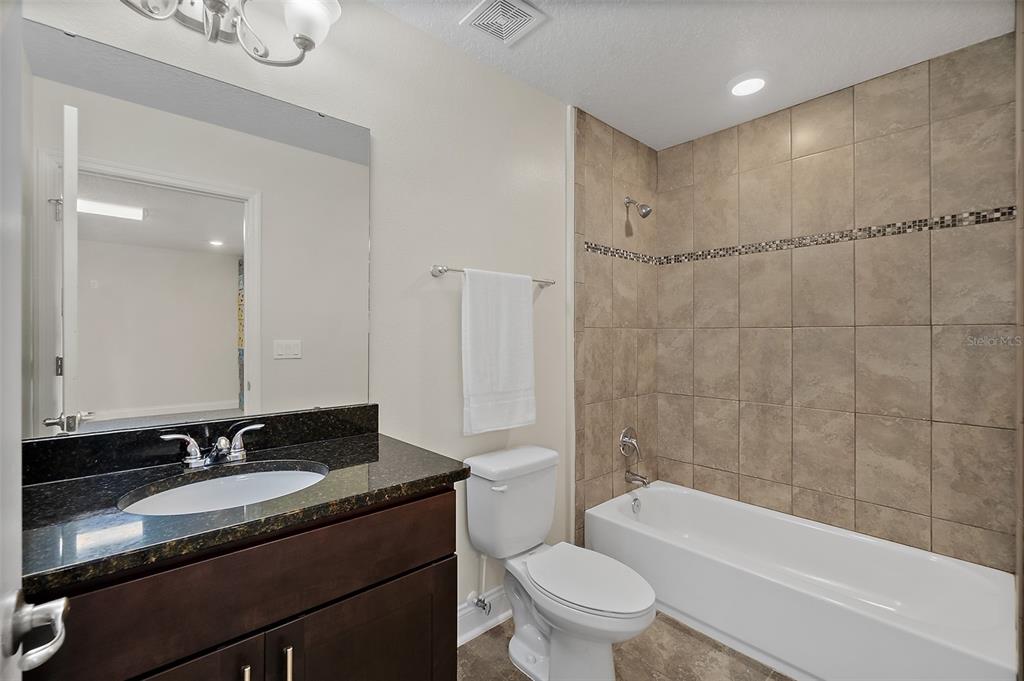 39 Turtle Ridge Drive Flagler Beach, FL 32136 - Photo 31 of 58 a bathroom with a granite countertop sink a toilet a mirror a bathtub and shower