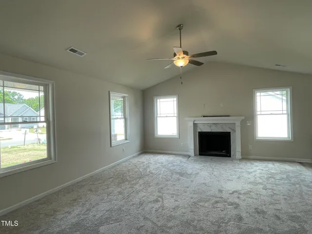 an empty room with windows fireplace and fan