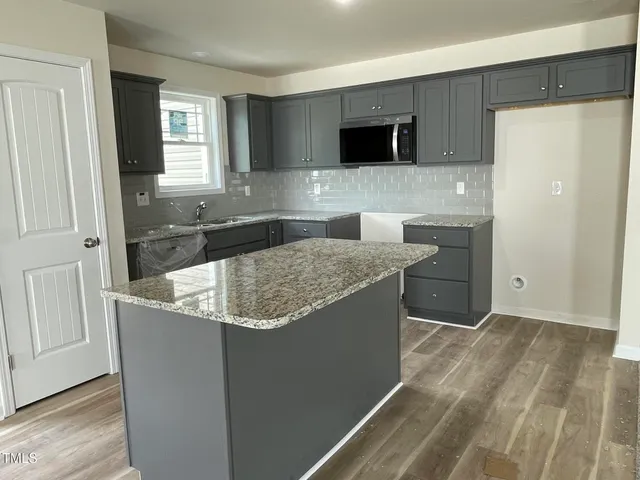 a kitchen with granite countertop a sink a stove and refrigerator
