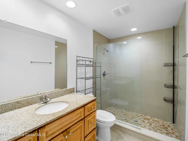 a bathroom with a granite countertop sink toilet mirror and shower