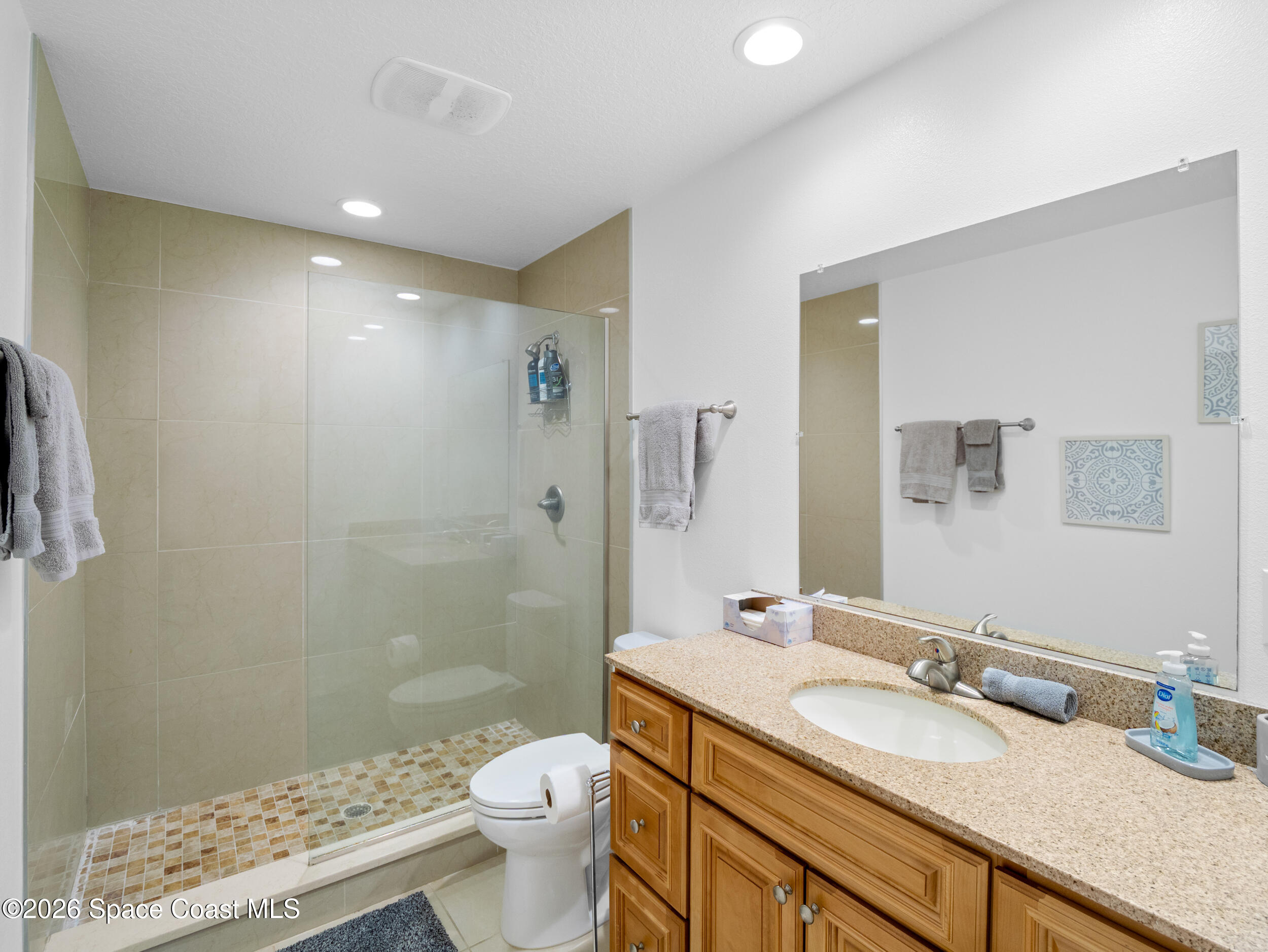 222 Rosa L Jones Drive Cocoa, FL 32922 - Photo 19 of 36 a bathroom with a granite countertop sink a toilet a mirror and shower