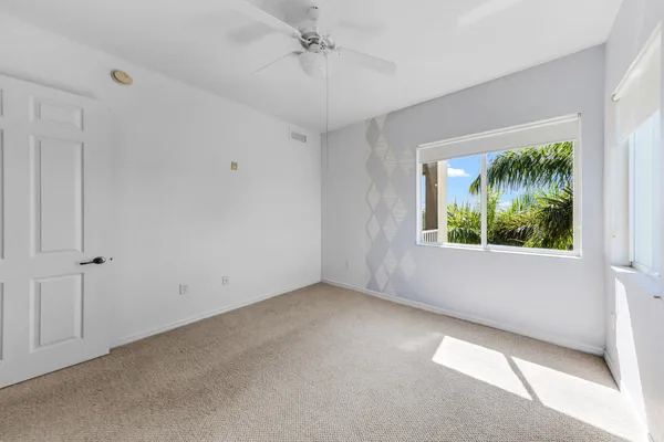 an empty room with a window and a ceiling fan