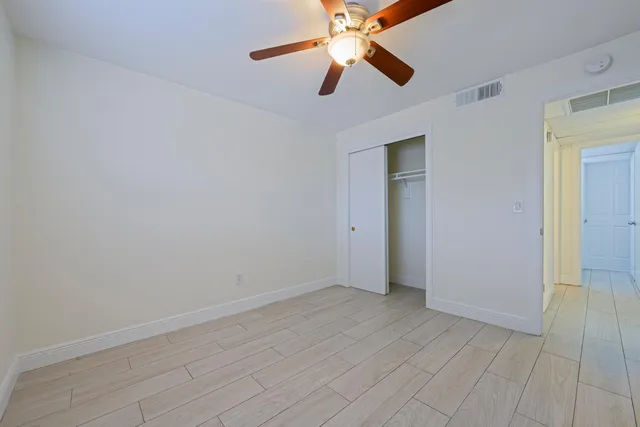 an empty room with closet and a ceiling fan