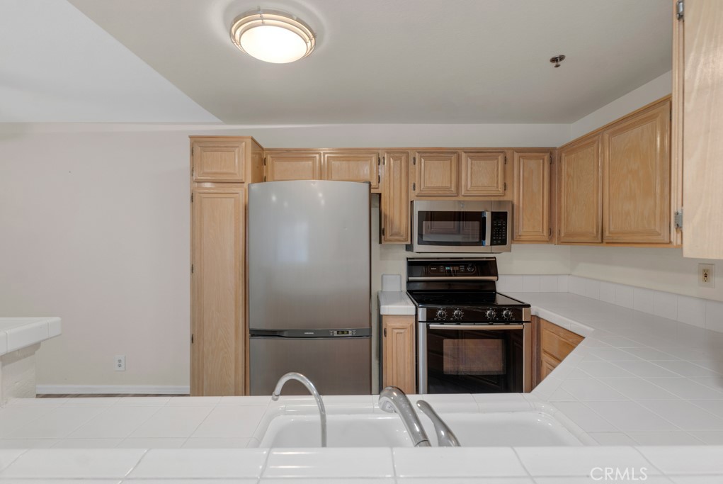 5744 Oak Bend Lane, Unit 203 Oak Park, CA 91377 - Photo 21 of 45 a kitchen with granite countertop a refrigerator and a stove top oven