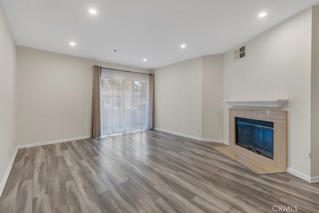 5744 Oak Bend Lane, Unit 203 Oak Park, CA 91377 - Photo 9 of 45 a view of an empty room with wooden floor fireplace and a window