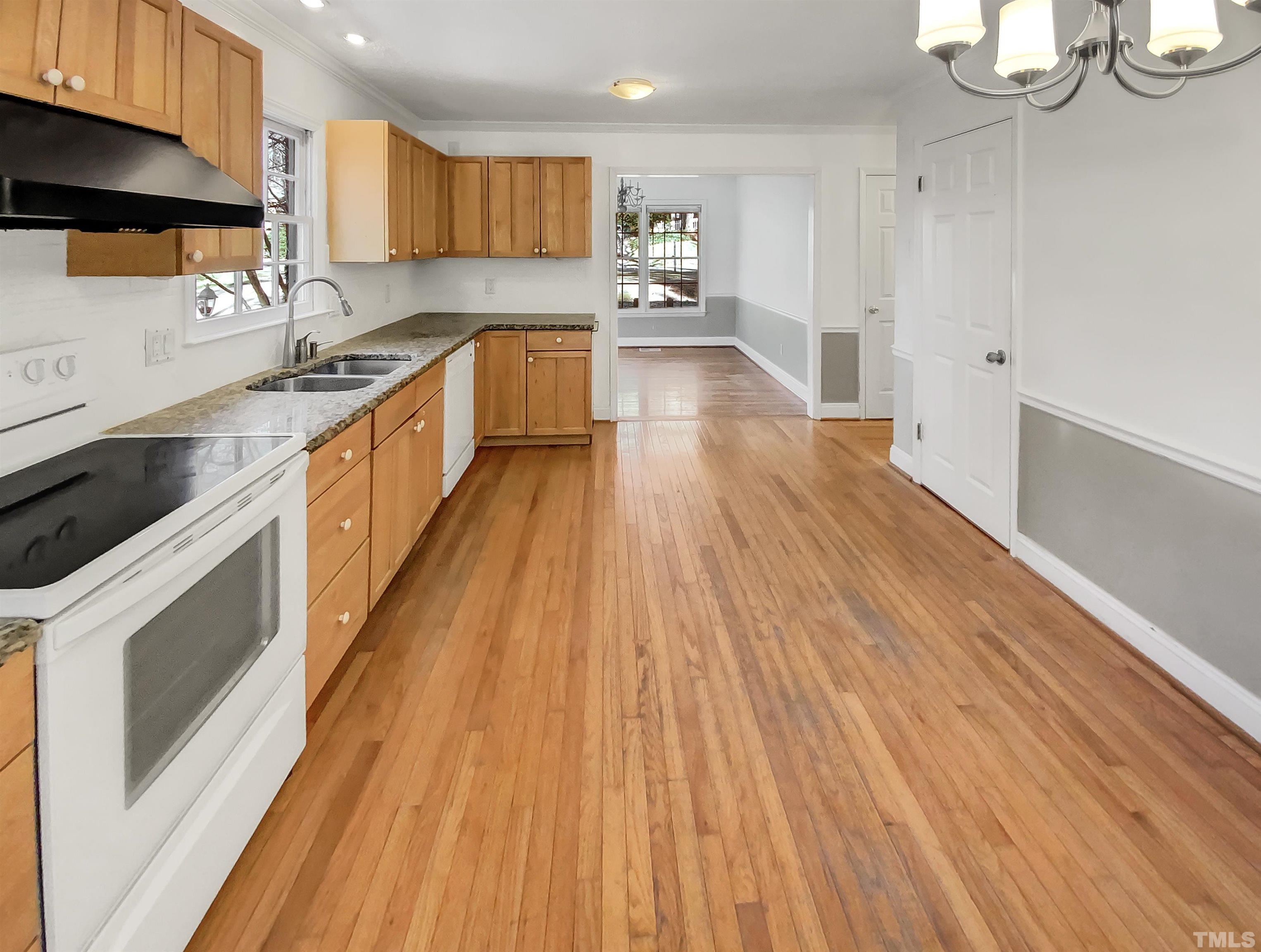 1007 Castalia Drive Cary, NC 27513 - Photo 11 of 17 a kitchen with granite countertop wooden floors stainless steel appliances and sink