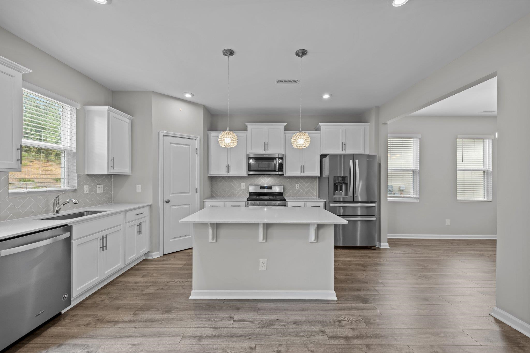 91 Stromness Path Clayton, NC 27527 - Photo 17 of 48 a kitchen with stainless steel appliances granite countertop a stove top oven a refrigerator a sink and dishwasher with wooden floor