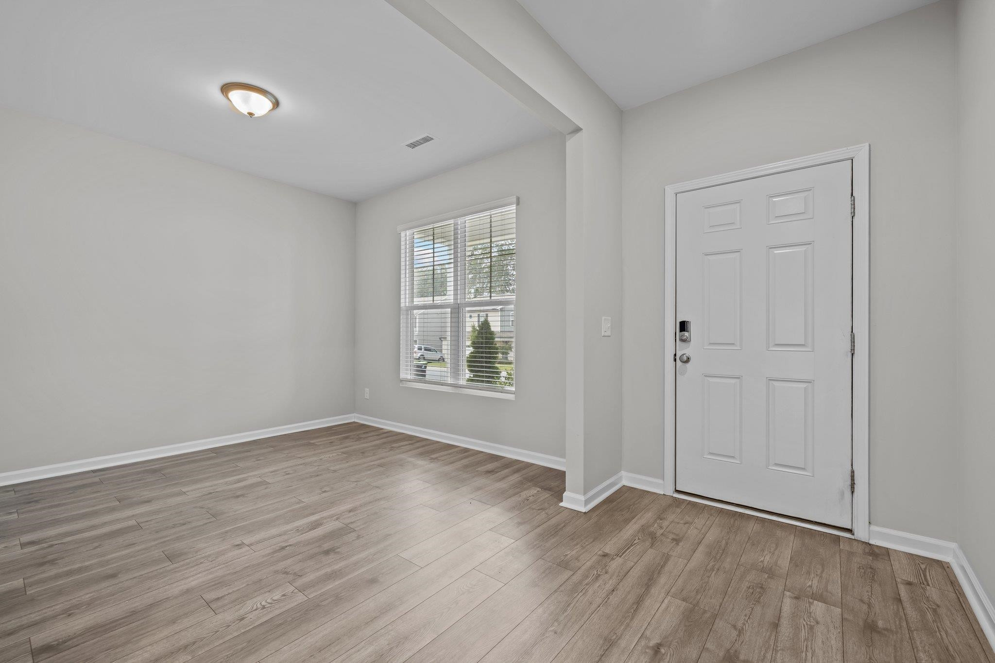 91 Stromness Path Clayton, NC 27527 - Photo 7 of 48 a view of an empty room with wooden floor and a window