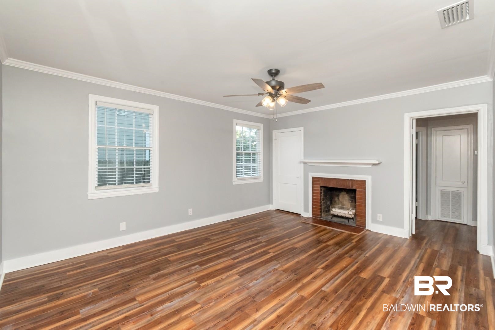 263 Border Drive East Mobile, AL 36608 - Photo 2 of 27 Spacious room featuring wood-finish flooring, a brick fireplace with a white mantel, and a ceiling fan with light fixture