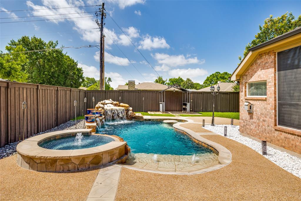 2100 Los Rios Boulevard Plano, TX 75074 - Photo 22 of 25 Resort-style backyard featuring a freeform swimming pool with rock waterfall, integrated spa, and expansive aggregate concrete decking