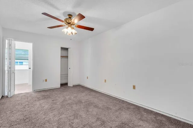 an empty room with closet and a ceiling fan