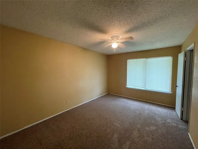 an empty room with a window and a ceiling fan