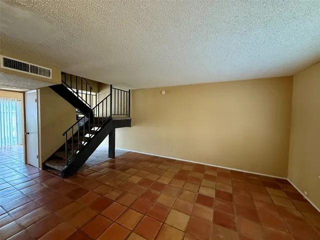 a view of an empty room with wooden floor and stairs