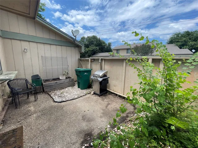 a backyard of a house with chairs plants and wooden fence
