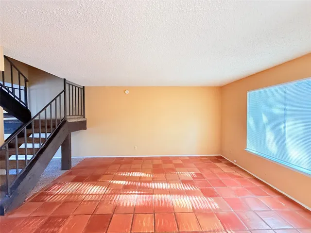 a view of an empty room with wooden floor and stairs