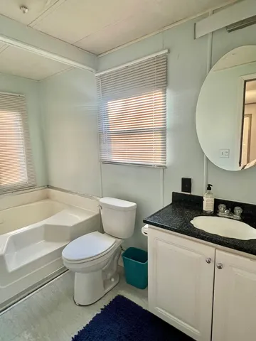 a bathroom with a granite countertop sink toilet a mirror and bathtub