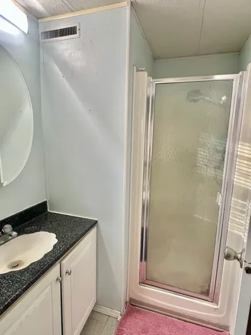 a bathroom with a granite countertop shower and a sink