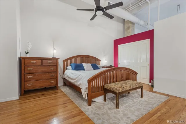 a bedroom with a bed a dresser and wooden floor