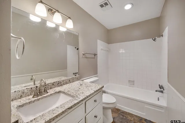 a bathroom with a granite countertop sink mirror toilet and bathtub