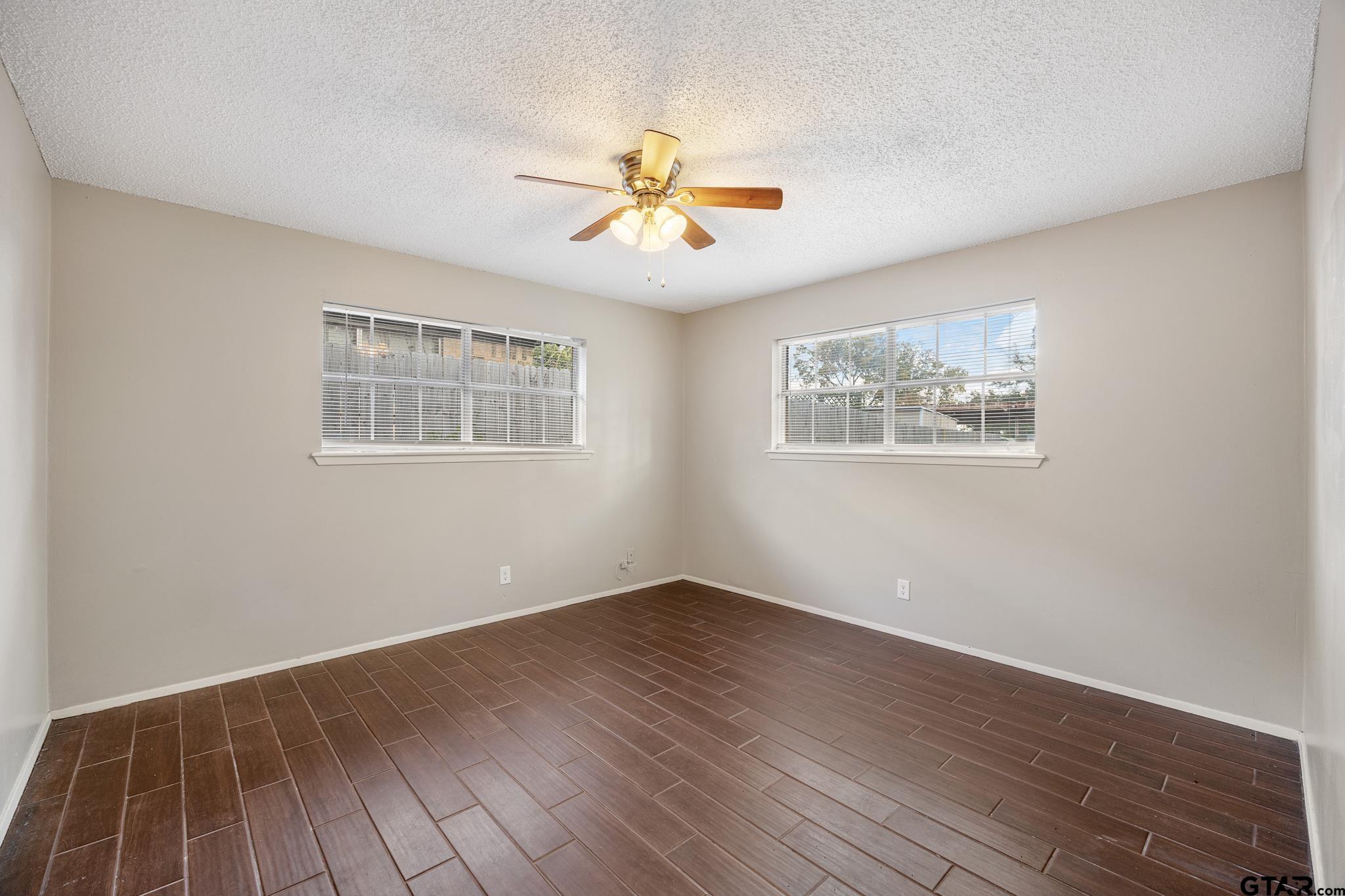 418 Boyd Lane Tyler, TX 75703 - Photo 16 of 25 a view of an empty room with wooden floor and a ceiling fan