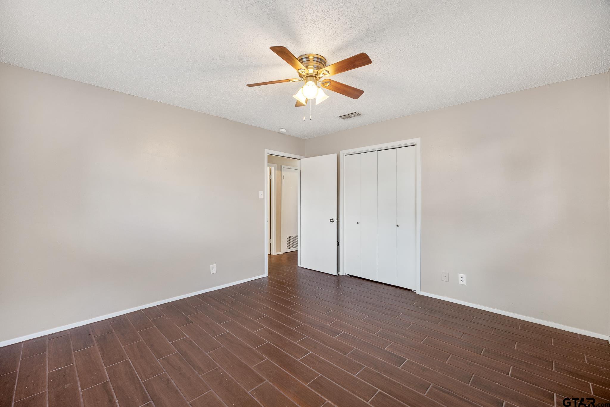 418 Boyd Lane Tyler, TX 75703 - Photo 17 of 25 a view of an empty room with wooden floor and a ceiling fan