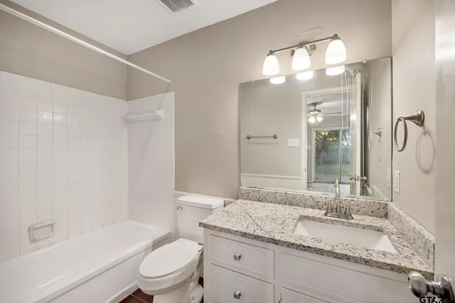 a bathroom with a granite countertop sink a toilet and a large mirror