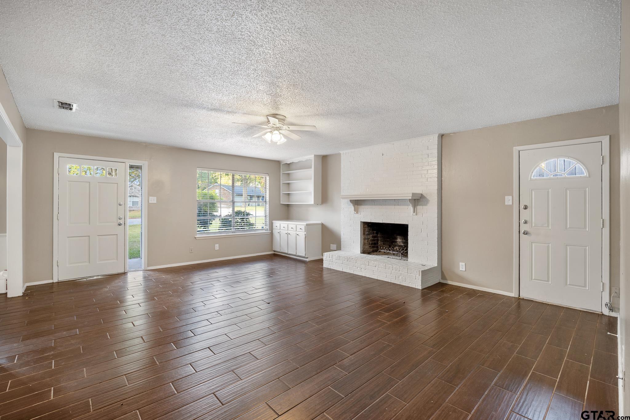 418 Boyd Lane Tyler, TX 75703 - Photo 5 of 25 an empty room with wooden floor fireplace and windows