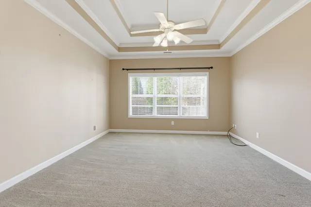 an empty room with a chandelier fan and windows