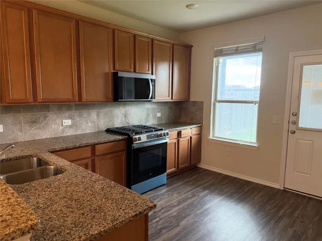 a kitchen with stainless steel appliances granite countertop a sink stove and microwave