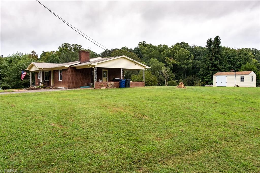Home features attached one-bay carport and outbuilding for additional storage. 