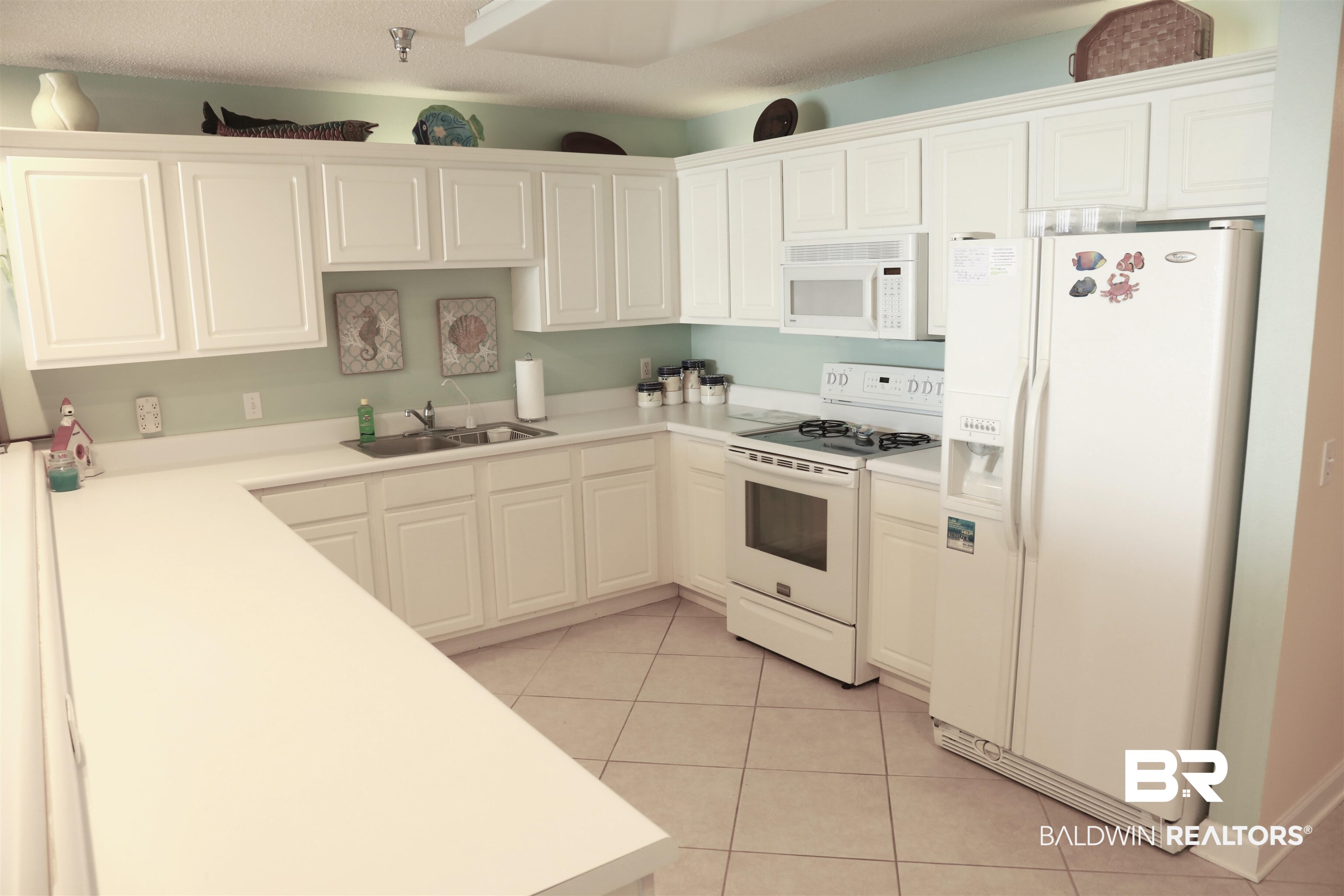 27770 Canal Road, Unit 308 Orange Beach, AL 36561 - Photo 9 of 16 Kitchen featuring white appliances, light countertops, and white cabinetry