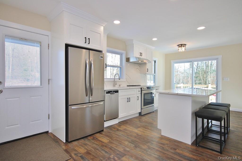 6 Buck Hill Road Wurtsboro, NY 12790 - Photo 11 of 43 a kitchen with a refrigerator a sink wooden floor and white cabinets