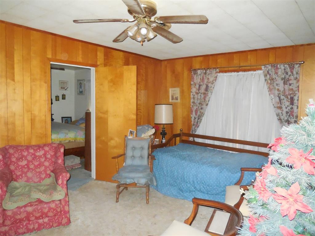 610 West Main Street Ranger, TX 76470 - Photo 2 of 17 Sitting room featuring ceiling fan, wood walls, carpet flooring, and crown molding