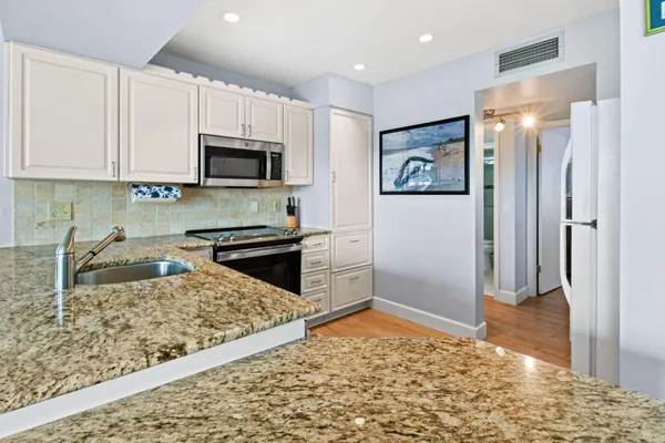a kitchen with stainless steel appliances granite countertop a refrigerator sink and stove