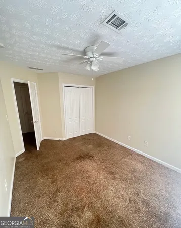an empty room with windows and fan