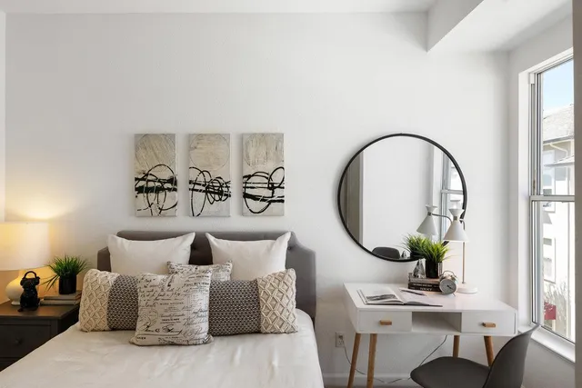 a bedroom with a bed mirror and table